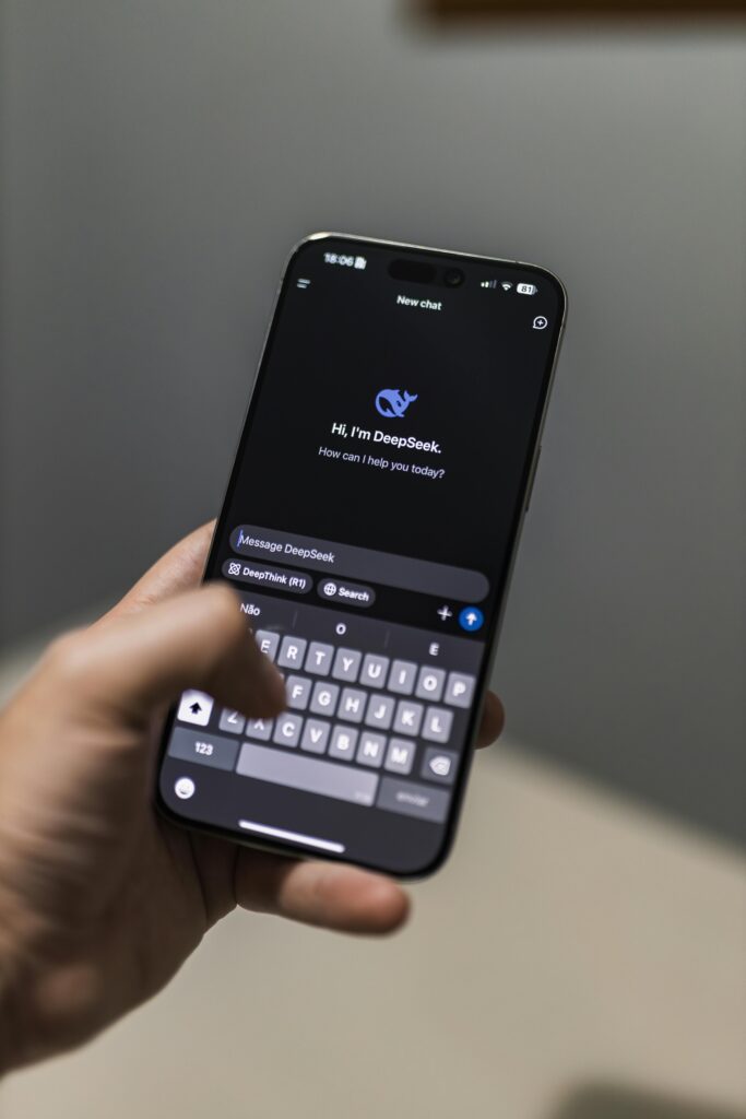 A hand holding a smartphone displaying an AI chat interface named DeepSeek, embodying modern technology.